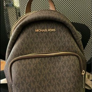 Little brown with dark MK lettering backpack used but good condition